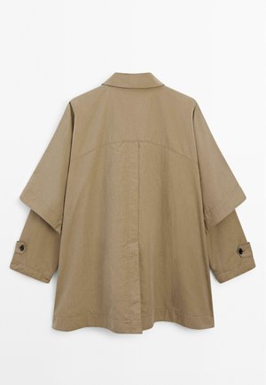 Beige oversized jacket with a pointed collar, short sleeves, and buttoned cuffs, featuring a smooth texture and minimalistic design.