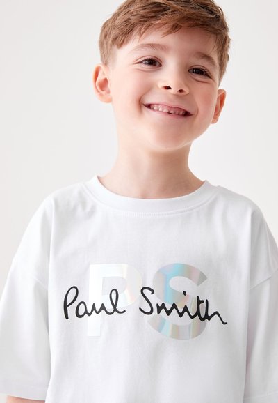Balts kokvilnas T-krekls ar "PS" spīdīgā sudrabā un melnā krāsā izšūtiem burtiem "Paul Smith" uz priekšpuses, īsām piedurknēm, ar apaļu kakla izgriezumu.