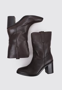 Brown leather ankle boots with a stacked heel, pointed toe, and subtle stitching details. Smooth texture with a sleek design.