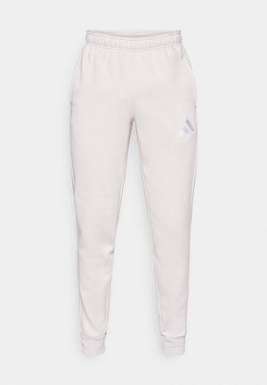 Ανοιχτό γκρι φόρμα με ελαστική μέση, στενά μπατζάκια και μικρό μωβ λογότυπο Adidas στο αριστερό μηρό. Κατασκευασμένο από λείο ύφασμα.