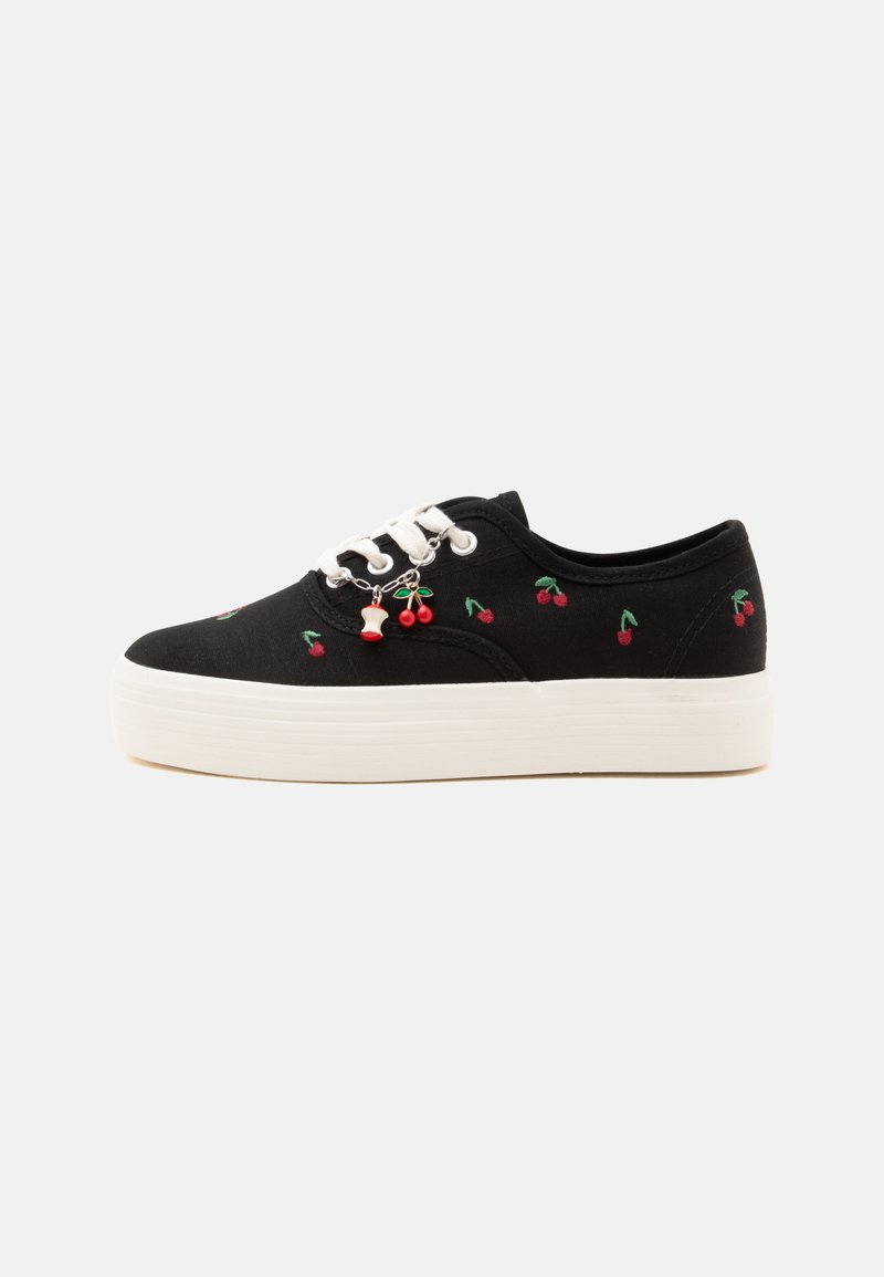 Basket plateforme noire avec lacets blancs, petites cerises rouges brodées et un charm cerise attaché aux œillets.