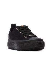 Las zapatillas de ante negro presentan una suela de goma gruesa, punta redondeada, diseño de cordones y una asa en el talón para facilitar su colocación.