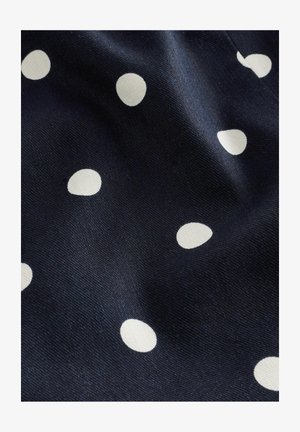 Marineblauer Stoff mit einer glatten Textur, der verstreute weiße Pünktchen in unterschiedlichen Größen zeigt. Das Design ist verspielt und rhythmisch.