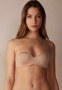 Naadloze strapless nude beha met gladde, gevormde cups, een naadloos ontwerp en lichtgewicht stof. Bevat subtiele stiksels en een ronde rand.