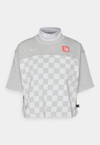 Pulover gri cu guler înalt, cu un model tablă de șah, mâneci scurte și o patch roșie. Fabricat dintr-un material moale din amestec de bumbac, cu o croială lejeră.