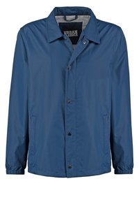 Modrá lehká bunda s druky, dvěma bočními kapsami, elastickými manžetami a šedou podšívkou límce.