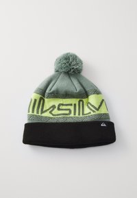 Bonnet en tricot avec un schéma de couleurs gris et noir, présentant un pompon sur le dessus, une bande jaune vif avec un texte graphique et une étiquette de logo.