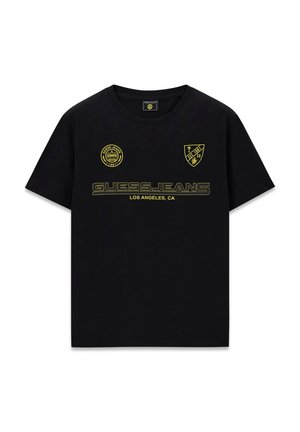 Schwarzes T-Shirt mit kurzen Ärmeln und gelbem "GUESS JEANS"-Logo, dem Schriftzug "LOS ANGELES, CA" sowie runden und schildförmigen Markenaufnähern auf der Brust.