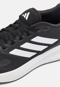 Černá sportovní obuv s prodyšným síťovinovým svrškem, bílými doplňky a logem se třemi pruhy, s texturovanou gumovou podešví označenou "CLOUDFOAM".