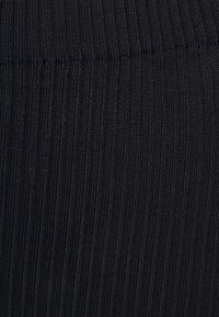 Černá žebrovaná tkanina s vertikálními pruhy, která má hladkou strukturu a pružnost, vhodná pro různé oděvní aplikace.