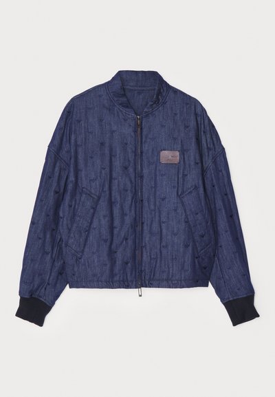 Džínová bomber bunda v tmavomodrej farbe s textúrovaným šitím, rebrovanými manžetami, predným zipsom a bočnými vreckami. Obsahuje malú nášivku s logom.