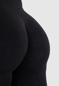 Czarne legginsy wykonane z elastycznego materiału, charakteryzujące się gładką fakturą i dopasowanym krojem, z wysokim stanem dla dodatkowego wsparcia.