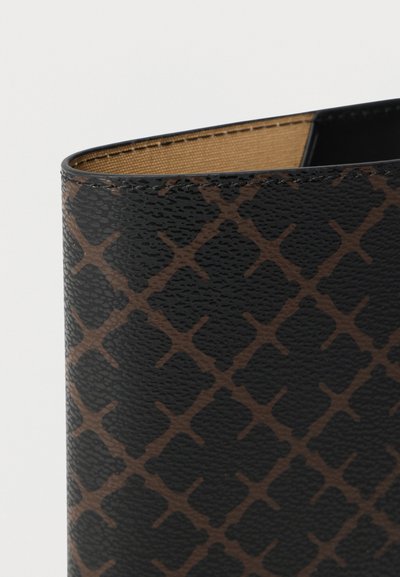 Εγγύς λήψη υφασμένης ζώνης σε μαύρο και καφέ με μοτίβο, με μπεζ εσωτερική επένδυση και εμφανείς ραφές κατά μήκος της πάνω άκρης.