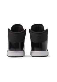 Black high-top sneakers with a glossy finish, padded collar, and white sole. Features the DC logo embossed on the back.
