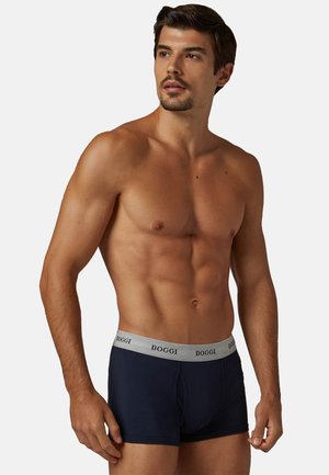 Boxer da uomo navy con elastico grigio recante il nome del marchio "BOGGI." Tessuto liscio, design aderente e lunghezza a metà coscia.