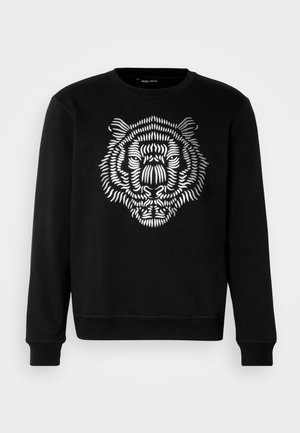 Crna dukserica s bijelim, detaljnim grafičkim prikazom tigra na prednjoj strani. Dizajn uključuje podebljane linije i teksturirani izgled.