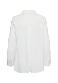 Chemise blanche à manches longues vue de dos avec une couture centrale et des poignets boutonnés sur un fond uni.