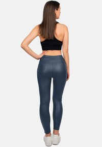 Hoge taille, marineblauwe leggings met een glanzende afwerking, gecombineerd met een zwarte cropped top. Draag ze met witte sneakers. Glad textuur, aansluitend ontwerp.