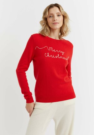 Pull rouge avec "Joyeux Noël" brodé en blanc, col rond, manches longues, et bords côtelés.