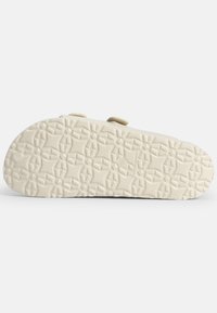 White rubber sole with a textured pattern featuring geometric shapes and accents, designed for grip and comfort.
