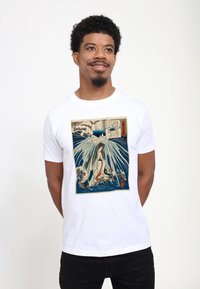 Bílý tričko s grafickým potiskem vln a postavy v tradičním stylu. Design obsahuje modré, béžové a červené akcenty.