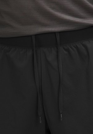 Crne sportske kratke hlače s elastičnim pojasom, opremljene podesivim vezicama. Materijal izgleda mekan i ima glatku teksturu.