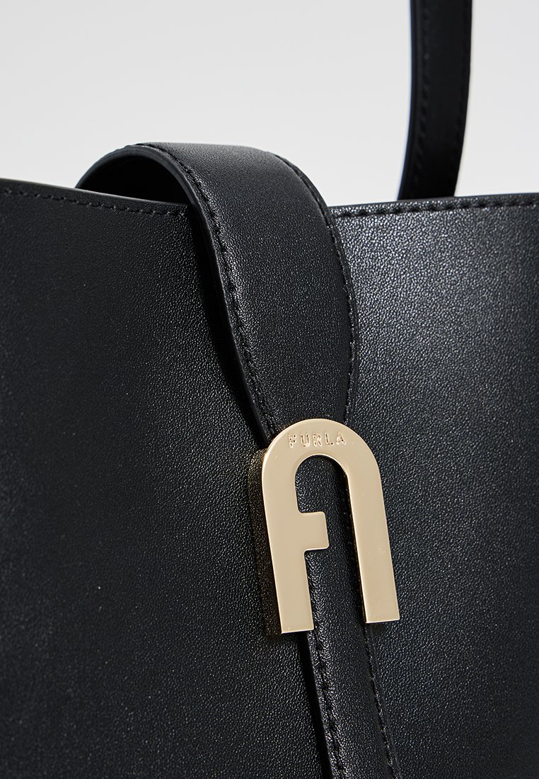 Borsa a tracolla in pelle nera con attacco logo in metallo dorato e superficie liscia, dal design strutturato e silhouette elegante e minimal.