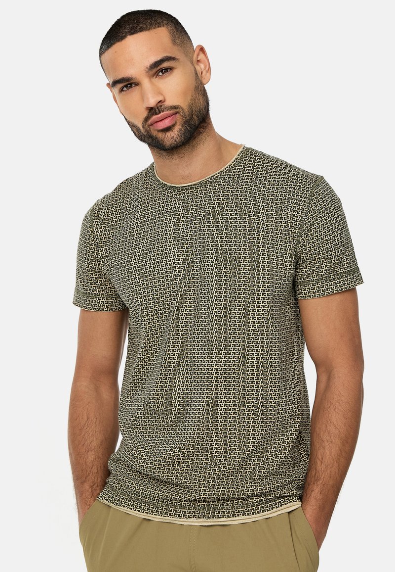 Kortærmet, fitted t-shirt i et grønt og cremefarvet geometrisk mønster med rund halsudskæring og glat bomuldsstof. Flade sømme og ingen synlige etiketter.