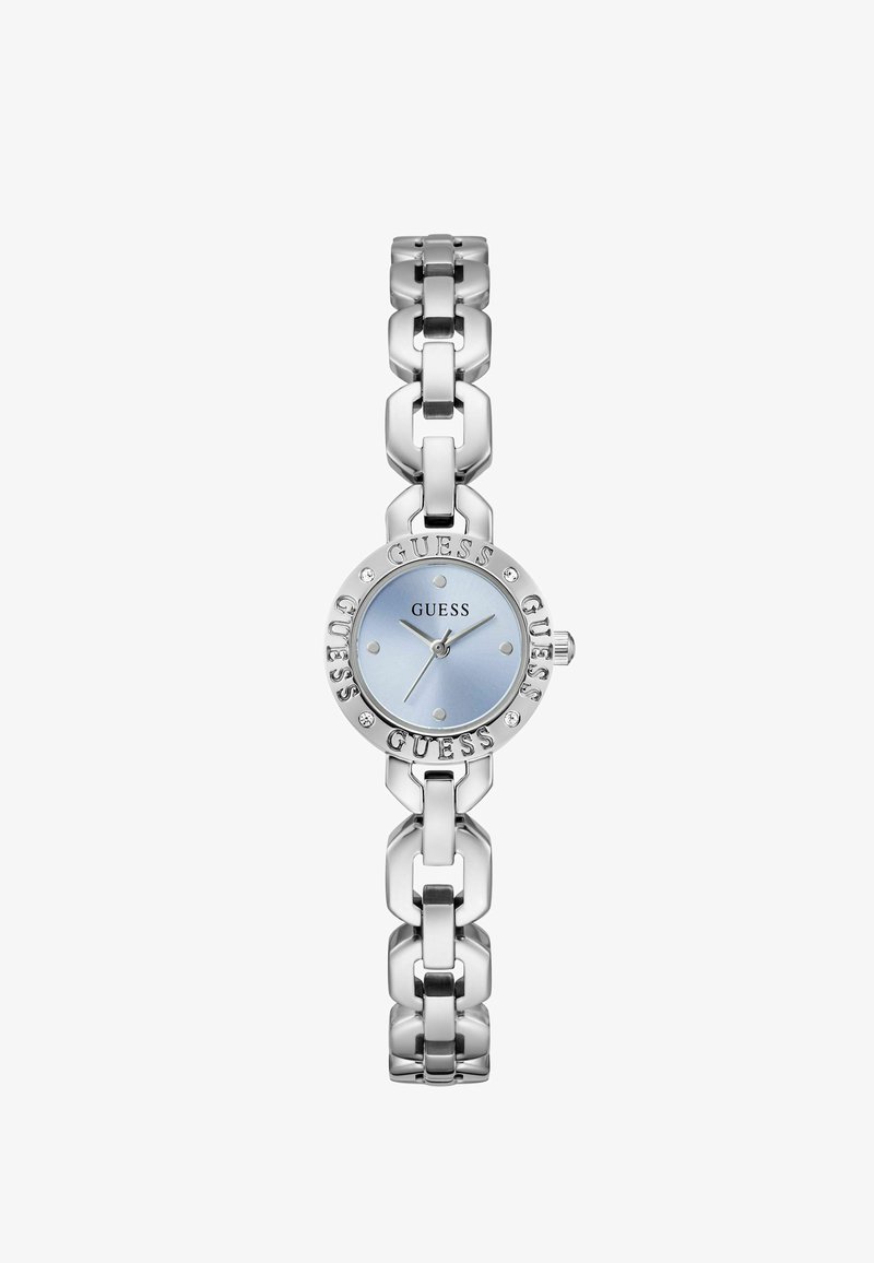 Montre-bracelet à maillons en métal argenté avec cadran rond bleu clair, marqueurs d'heure minimalistes, et logo GUESS sur la lunette et le cadran.
