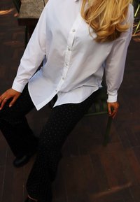 Valge pikkade varrukatega särk, millele on lisatud mustad laienevad püksid valgete täppidega. Tekstuuriga kangas ja mugav lõige.