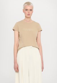 Beige tričko s kulatým výstřihem a krátkými rukávy, na přední straně s bílým potiskem loga "Armani Exchange Milano/New York".