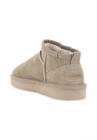 Botines de ante beige con forro interior suave, punta redondeada y detalles de costura visibles. Presentan una etiqueta de marca en el talón.
