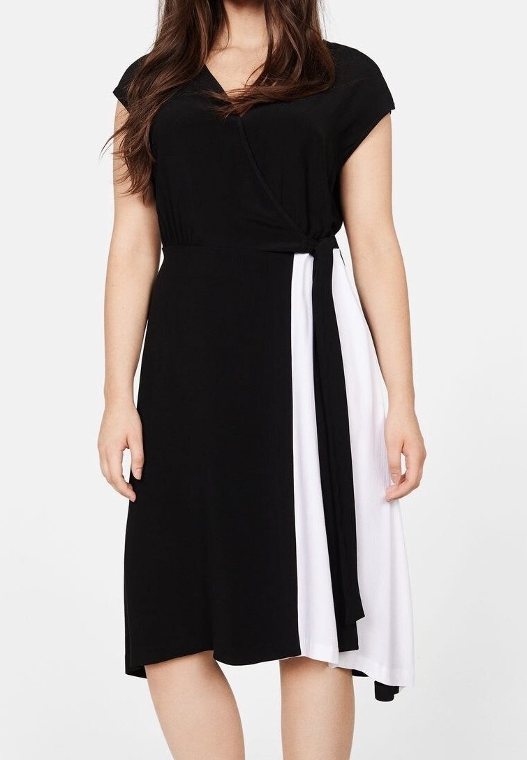 Schwarzes und weißes Wickelkleid mit kurzen Ärmeln, einem V-Ausschnitt und einem fließenden Design. Die linke Seite ist schwarz, die rechte Seite ist weiß.