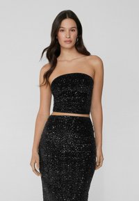 Zwart pailletten tweedelig set met een strapless top en een aansluitende rok, beide met een gestructureerd bloemenpatroon en een glanzende afwerking.