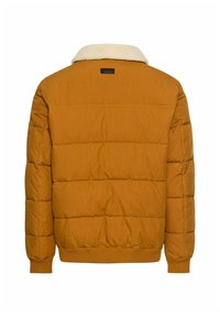 Mosterdgele pufferjack met een schapenvacht kraag, geweven ontwerp, elastische manchetten en zoom, met een rechthoekig merklabel op de achterkant.