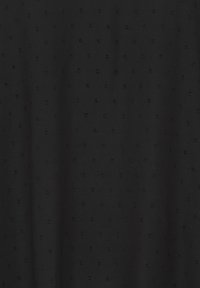 Tissu noir avec une texture subtilement ponctuée formant un motif de grille répétitif sur la surface.