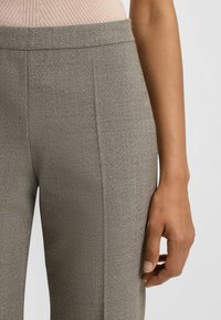 Grau maßgeschneiderte Hosen mit einem strukturierten Muster. Sie verfügen über eine schlanke Passform mit einem glatten Bund und dezenten Seitennähten. Der Stoff wirkt leicht.
