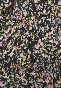 Svart tyg med ett blommönster i pastellrosa, gult och grönt. Samlad textur med volanger för extra volym.