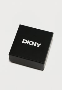 Cutie neagră cu un finisaj neted, având logo-ul alb "DKNY" în partea de sus. Design simplu, minimalist, fără modele suplimentare.