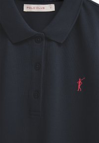 Polo bleu marine avec trois boutons, logo brodé d'un joueur de polo rouge sur la poitrine, et étiquette "POLO CLUB" taille S à l'intérieur du col.