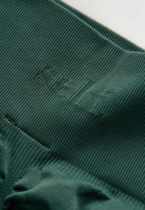 Grüner, gerippter Stoff mit strukturierter Oberfläche und geprägt Logo. Das Design zeichnet sich durch eine glatte, elastische Qualität und minimale Details aus.