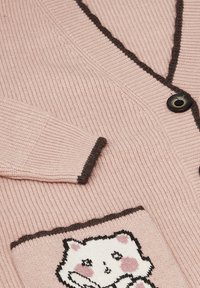 Rosa ribbat cardigan med mörkbruna detaljer, med knappstängning och en framficka med kattdesign. Mjuk textur.