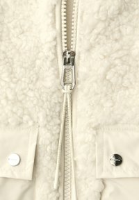 Weiße Fleecejacke mit durchgehendem Reißverschluss aus Metall, strukturierter Stoff und Druckknöpfen an zwei Fronttaschen.