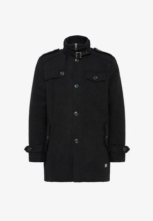 Svart ullkåpe med høy krage, frontglidelås, dobbeltknappede knapper, sidelommer og epaulettes på skuldrene. Glatt tekstur.