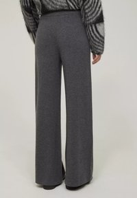 Graue, weit geschnittene Hosen aus einem weichen, strukturierten Stoff. Mit einem elastischen Bund und einer lockeren Passform, die bis zu den Knöcheln reicht.