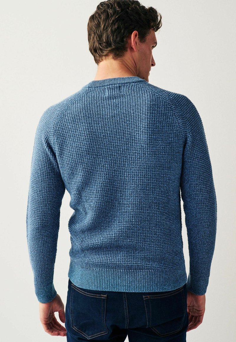Blauwe gebreide trui met een getextureerde stof, geribde manchetten en zoom, en een ronde halslijn, gezien vanuit de achterkant. Geschikt voor casual gebruik.