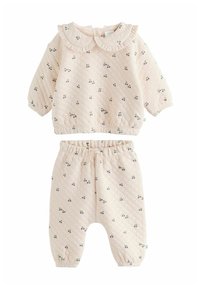 Completo per neonati in due pezzi realizzato in tessuto trapuntato color crema, con stampa di ciliegie, top con colletto Peter Pan con volant e pantaloni abbinati con vita elastica.