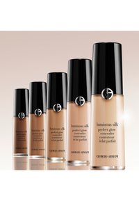 Cinq flacons de correcteur Giorgio Armani Luminous Silk Perfect Glow dans des teintes graduées du foncé au clair avec des bouchons noirs.