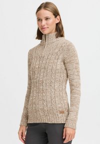 Beige kabelstrickpullover mit hohem Kragen und gerippten Bündchen; verfügt über ein strukturiertes Muster und ein dezentes Logo-Tag am Saum.