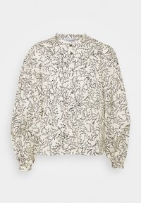 Blouse longue à manches longues de couleur crème avec un motif de branche de feuilles noires, poignets froncés, petit col à volants et patte de boutonnage à moitié ouverte.